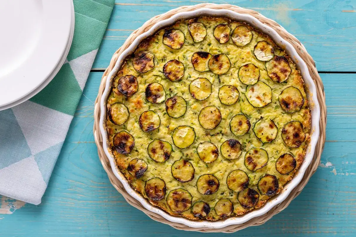 Tortino di zucchine dorato e invitante, con fette di zucchine grigliate disposte a regola d'arte sulla superficie.