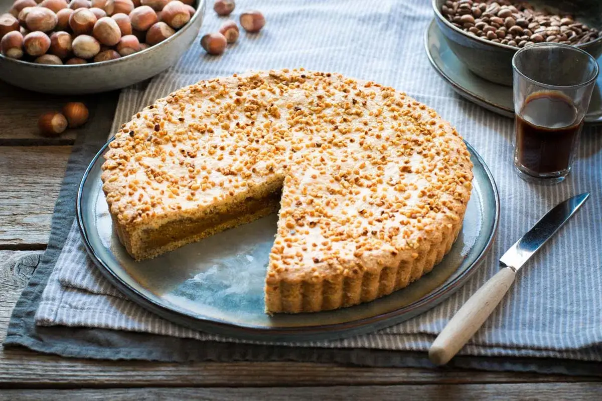 Torta alla Nutella, ricoperta di nocciole tritate, pronta per essere gustata con un caffè.