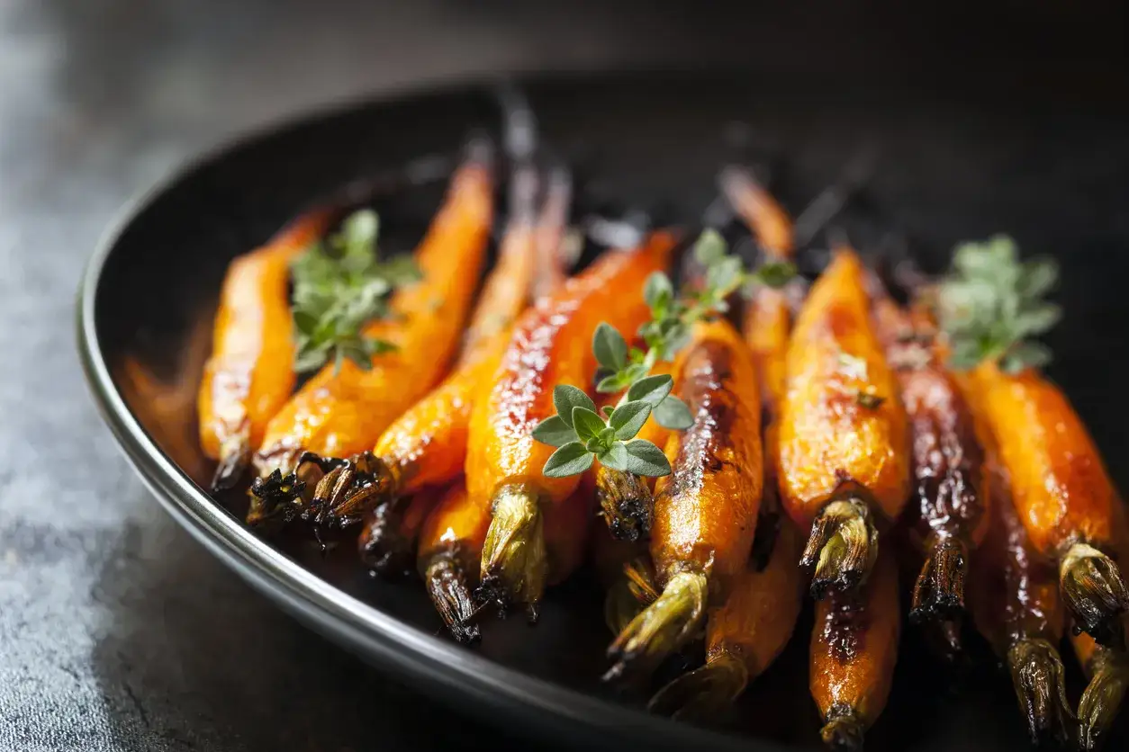 Carote caramellate e tenere, cotte alla perfezione nella friggitrice ad aria, guarnite con erbe aromatiche fresche.