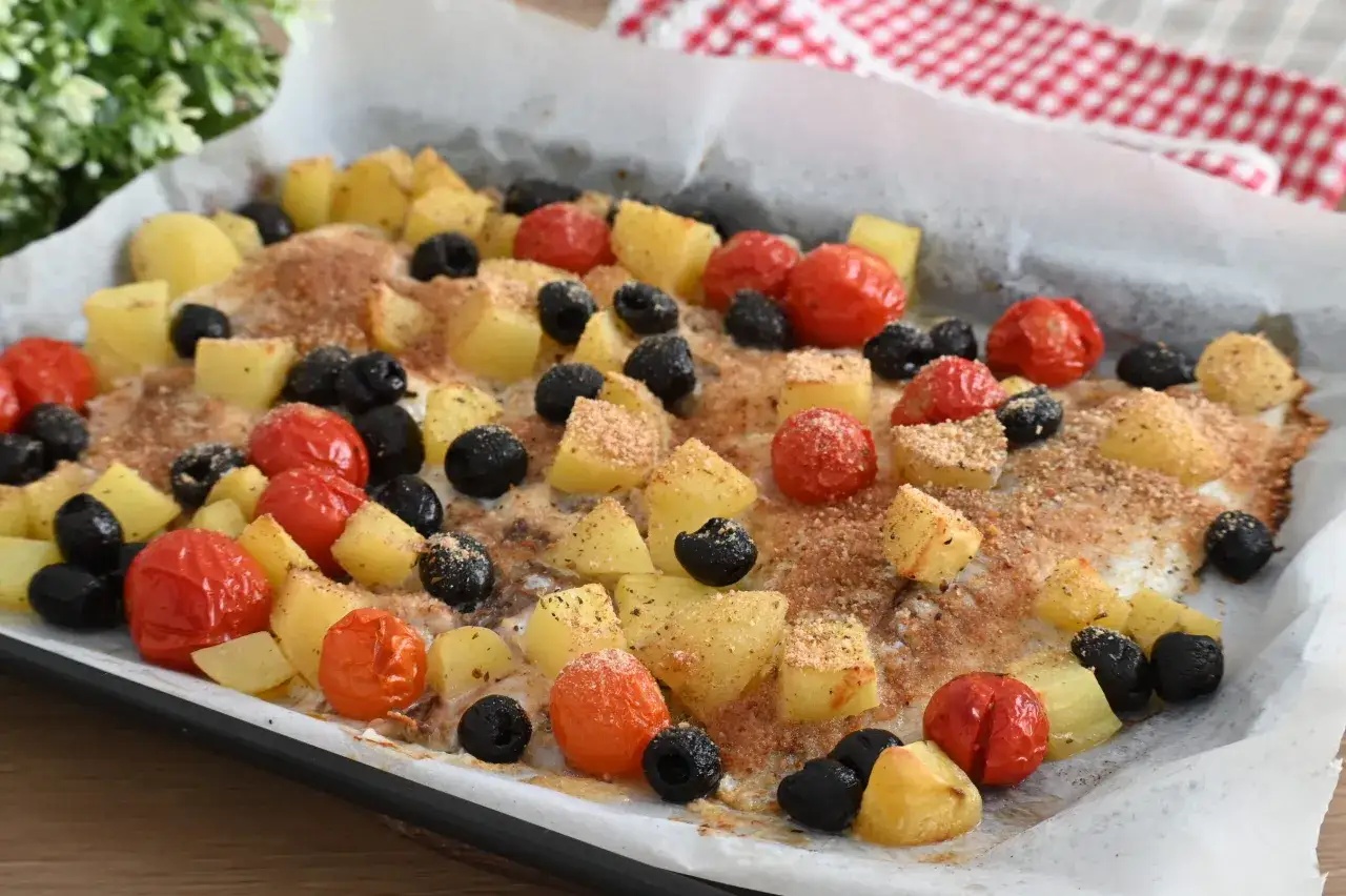 Orata al forno con patate, pomodorini e olive nere, un piatto saporito e colorato pronto per essere gustato.