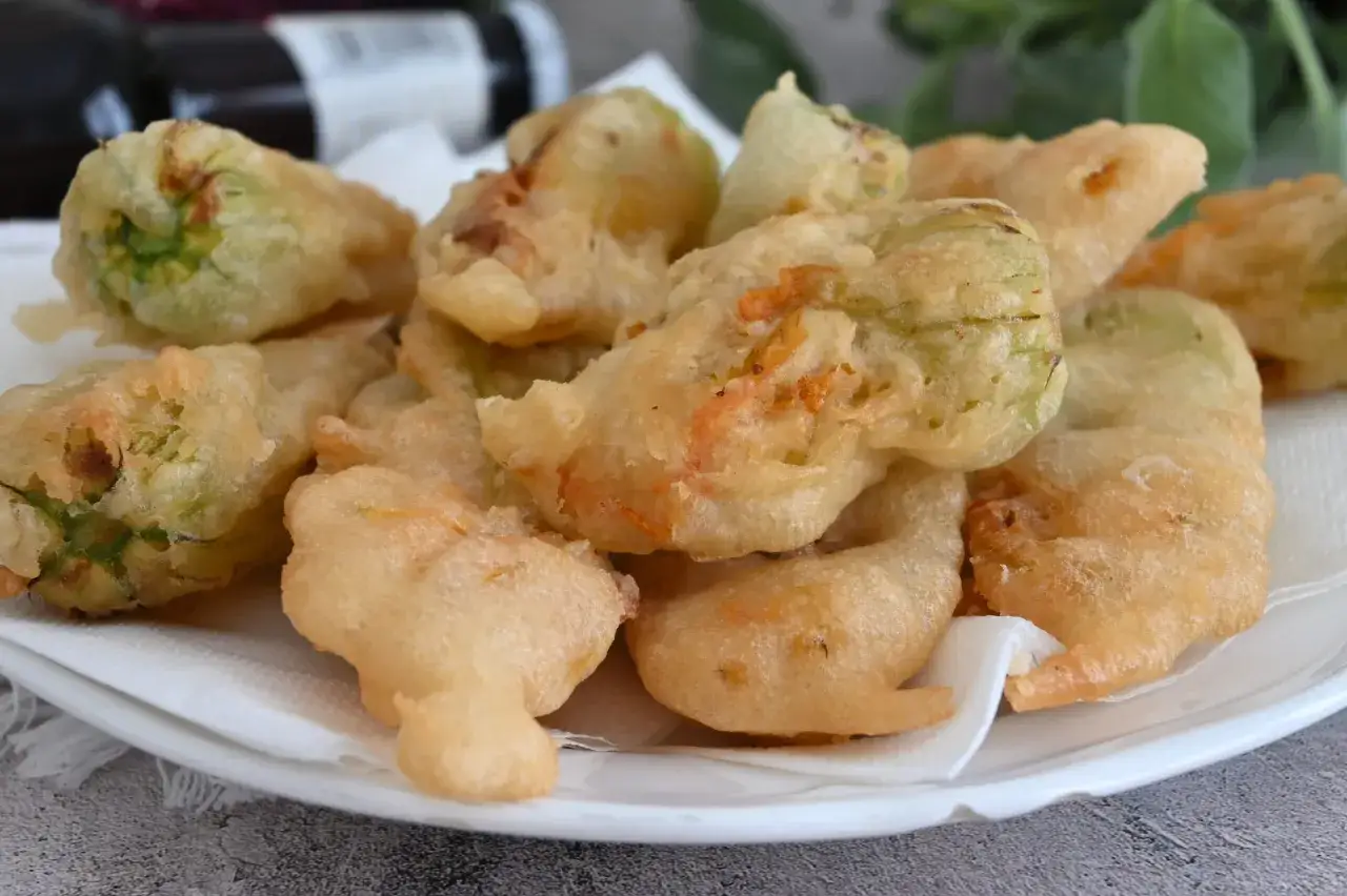 Un piatto di croccanti fiori di zucca in pastella, dorati e invitanti, pronti per essere gustati.