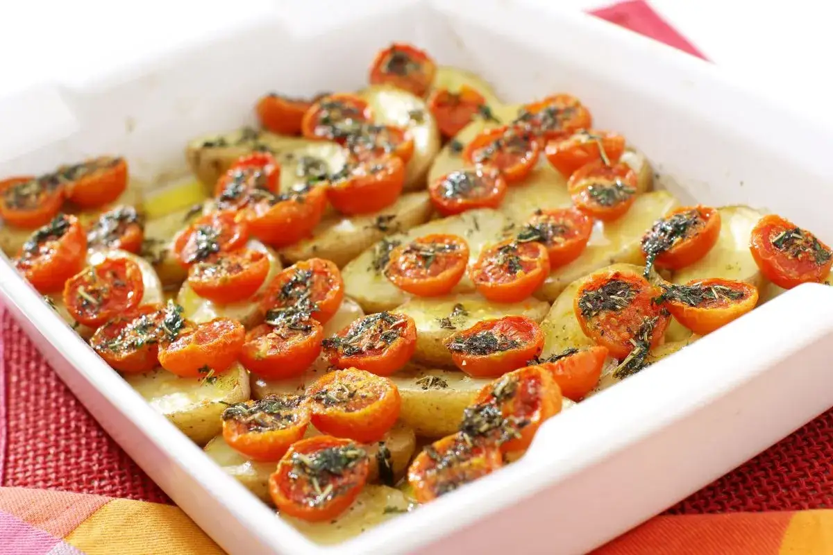 Pomodori gratinati al forno con patate, conditi con erbe aromatiche. Un piatto semplice e gustoso, pronto per essere infornato.