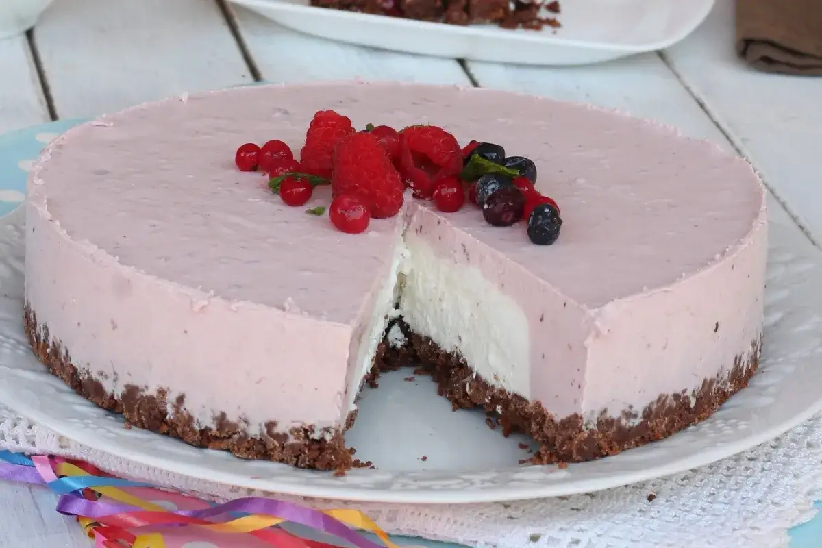 Deliziosa torta fredda allo yogurt con base croccante, guarnita con frutti di bosco freschi. Perfetta per ogni occasione.