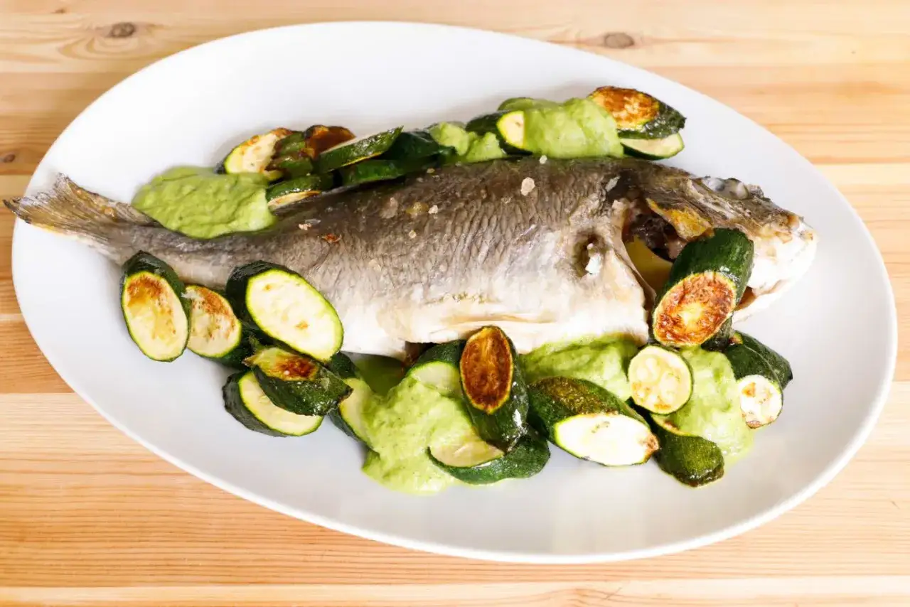 Filetti di orata al forno con zucchine saltate e salsa verde cremosa. Un piatto leggero e saporito, perfetto per un pasto sano.