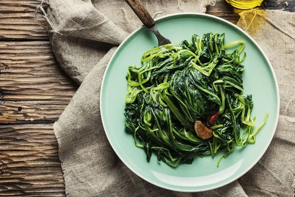 Piatto di puntarelle in padella, condite con aglio e peperoncino, pronte per essere gustate.