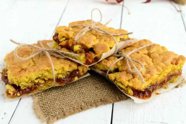 Tre fette di torta con marmellata, legate con spago, su carta da forno e tela di juta.