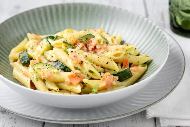 Penne con salmone e zucchine, un piatto cremoso e saporito, condito con erbe fresche e pepe nero.