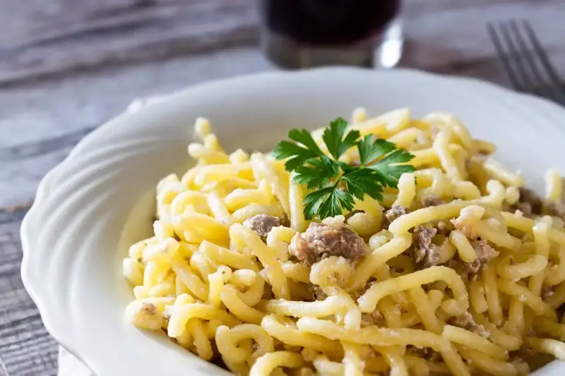 Piatto di pasta con salsiccia sbriciolata, condita con un sugo cremoso e guarnita con prezzemolo fresco.