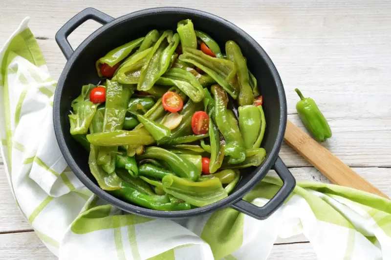 Friggitelli in padella, saltati con pomodorini e aglio, pronti per essere gustati.